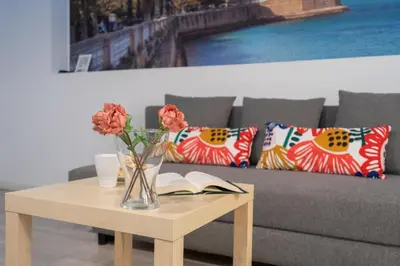 a vase of flowers on a table next to a couch at CDZ - Bella in Cádiz