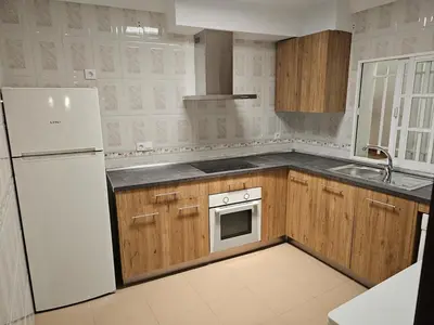 a kitchen with wooden cabinets and a white refrigerator at La Casita in Chiclana de la Frontera