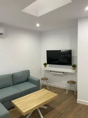 a living room with a blue couch and a tv at apartamento en centro in Chipiona