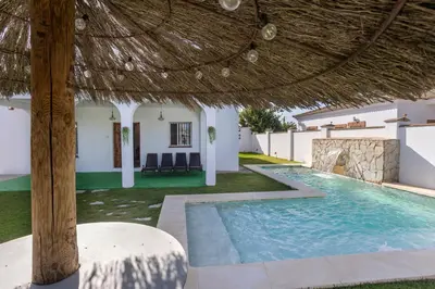 a villa with a swimming pool and a straw umbrella at Montijo Relax and Sunny Private Pool in Cádiz