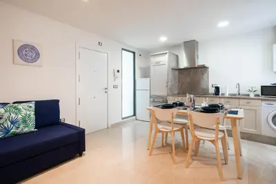 a kitchen with a table and chairs and a blue couch at CDZ - Cristóbal Colón in Cádiz