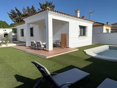 a backyard with a patio with chairs and a pool at Casita de Mar in Conil de la Frontera