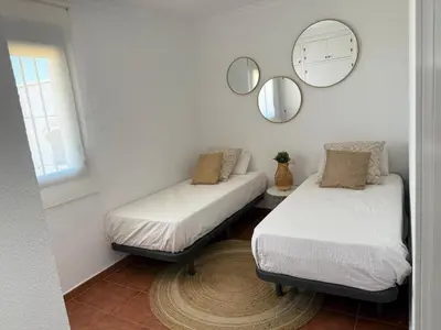 two beds in a room with a mirror on the wall at Casita de Mar in Conil de la Frontera