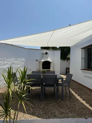 a patio with a table and chairs and a grill at Casita de Mar in Conil de la Frontera