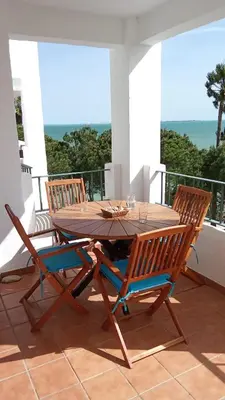 a wooden table and chairs on a balcony with the ocean at Casa Ensenada by 7Escalones in Rota