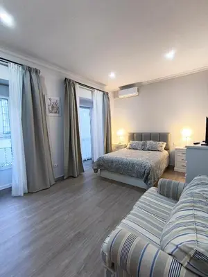 a bedroom with a bed and a couch and windows at Casa San Juan 55 - Centro Sanlúcar in Sanlúcar de Barrameda