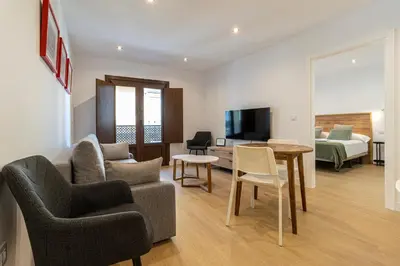 a living room with a couch and a table and a bed at Allo Apartments Medina II Centro 1 Habitación in Jerez de la Frontera