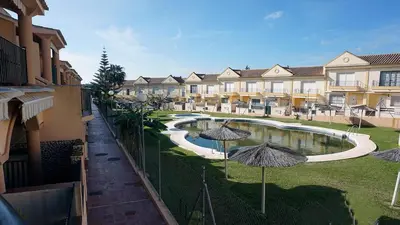 an apartment complex with a swimming pool and umbrellas at Apartamento Urb Al Andalus A un paseo de la playa de la Barrosa in Novo Sancti Petri