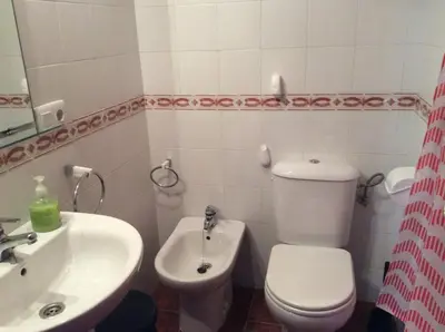 a bathroom with a white toilet and a sink at Apartamento Urb Al Andalus A un paseo de la playa de la Barrosa in Novo Sancti Petri