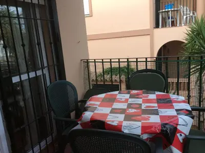 a table and chairs on a balcony with a quilt on it at Apartamento Urb Al Andalus A un paseo de la playa de la Barrosa in Novo Sancti Petri