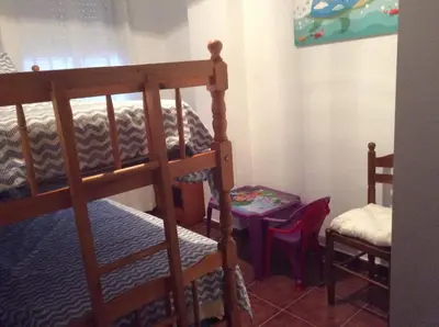 a bedroom with two bunk beds and a table at Apartamento Urb Al Andalus A un paseo de la playa de la Barrosa in Novo Sancti Petri