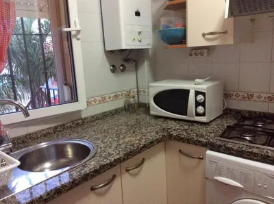 a kitchen with a sink and a microwave on a counter at Apartamento Urb Al Andalus A un paseo de la playa de la Barrosa in Novo Sancti Petri