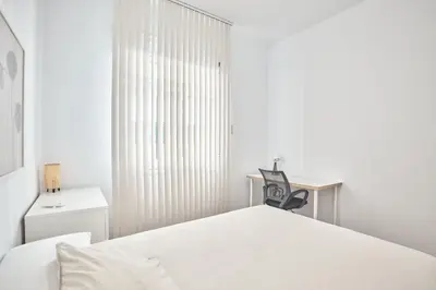 a white bedroom with a bed and a chair at Cuca Rooms by Cadiz Time in Cádiz