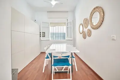 a dining room with a white table and blue chairs at Cuca Rooms by Cadiz Time in Cádiz