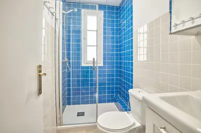 a blue tiled bathroom with a toilet and a shower at Cuca Rooms by Cadiz Time in Cádiz