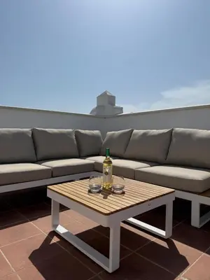 a couch and a table with a bottle on it at Ático Sabina free parking by staycare in Rota