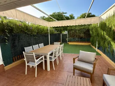 a patio with a wooden table and chairs and a garden at Dúplex El Lago free parking by staycare in Rota