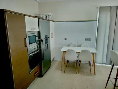 a kitchen with a table and chairs and a refrigerator at Modern 3-Bedroom Villa with Private Pool & BBQ in Cádiz