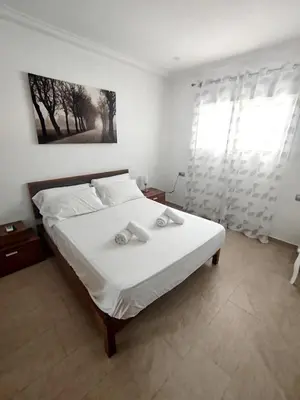 a bedroom with a bed with white sheets and a window at Modern 3-Bedroom Villa with Private Pool & BBQ in Cádiz