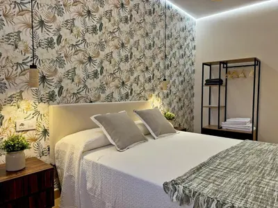 a bedroom with a bed and a floral wallpaper at Casa Las Mironas II - Ole Solutions in El Puerto de Santa María