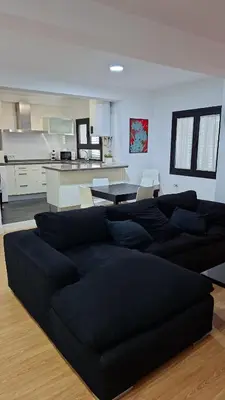 a black couch in a living room with a kitchen at Góngora 2 in Chipiona