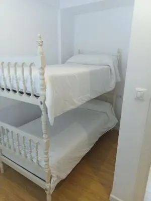 a bedroom with two bunk beds with white sheets at Góngora 2 in Chipiona