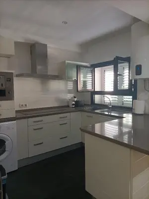 a kitchen with white cabinets and a stove top oven at Góngora 2 in Chipiona