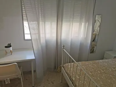 a bedroom with a bed and a desk and a window at Se alquilan habitaciones in Jerez de la Frontera