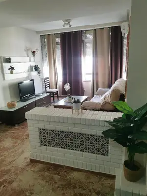 a living room with a brick fireplace with a tv at Se alquilan habitaciones in Jerez de la Frontera