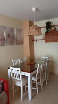 a dining room table with white chairs and a table and a light at Villa León in Chipiona