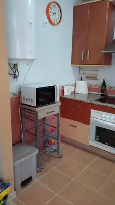 a kitchen with a microwave and a clock on the wall at Villa León in Chipiona
