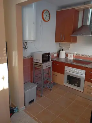 a kitchen with a stove and a clock on the wall at Villa León in Chipiona