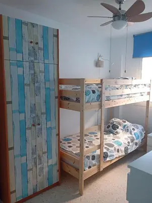 two bunk beds in a room with a ceiling fan at Villa León in Chipiona