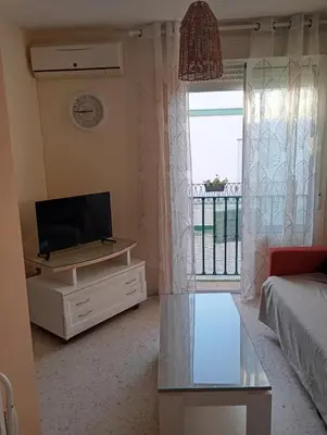a living room with a tv and a couch and a window at Villa León in Chipiona