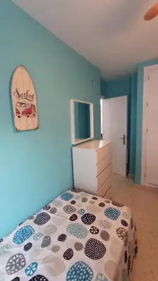 a bedroom with a bed and a blue wall at Villa León in Chipiona