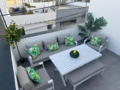 a table and pillows on a balcony with a bench at Ático Safari in Sanlúcar de Barrameda