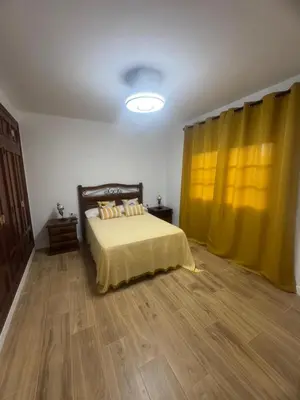 a bedroom with a bed and a yellow curtain at Ático Safari in Sanlúcar de Barrameda