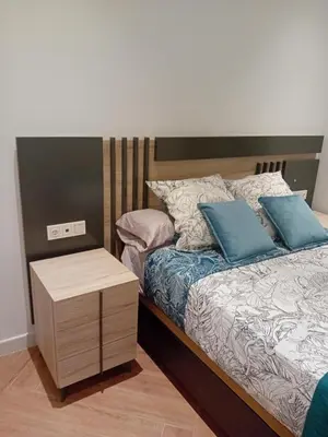 a bed with blue pillows and a night stand at San juan 32 bajo E in Sanlúcar de Barrameda