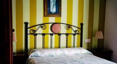 a bed in a room with yellow and white stripes at HOTEL Paquita in Chipiona
