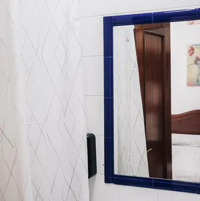 a mirror with a blue frame in a room at HOTEL Paquita in Chipiona