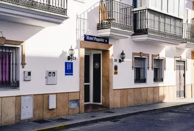 a building with a sign on the side of a street at HOTEL Paquita in Chipiona