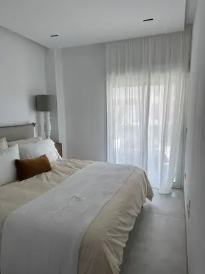 a white bedroom with a large bed and a window at Oasis Ballena Exclusive in Cádiz