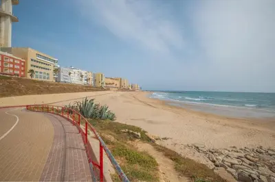 a beach with a red fence next to the ocean at Pez Austral in Cádiz