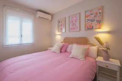 a bedroom with a large bed with pink sheets and pillows at Pez Austral in Cádiz