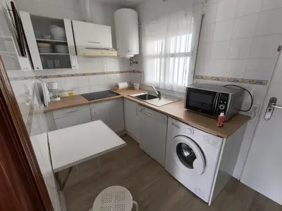 a small kitchen with a washing machine and a microwave at Playasol in Chiclana de la Frontera