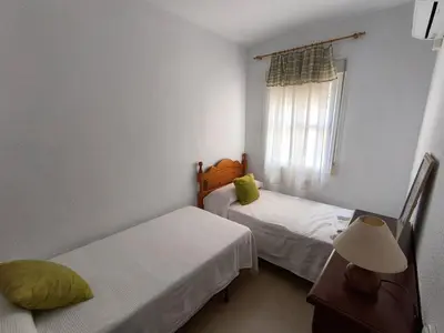 a small room with two beds and a window at Playasol in Chiclana de la Frontera
