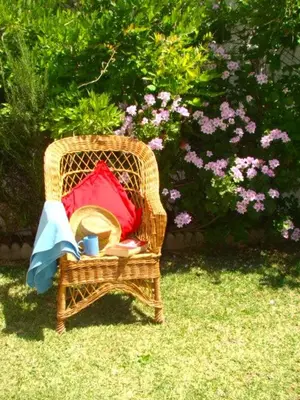 a wicker chair with a hat and red pillows at Villa Las Cármenes in Conil de la Frontera