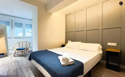 a bedroom with a large bed and a chair at En la Orilla del Mar Grupo AC Gestion in Cádiz
