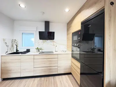 a kitchen with wooden cabinets and a black refrigerator at En la Orilla del Mar Grupo AC Gestion in Cádiz