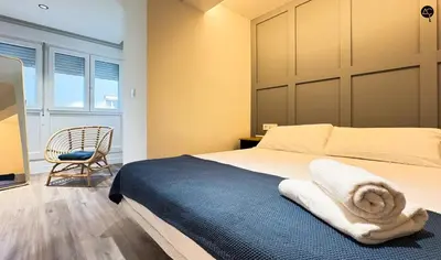 a bedroom with a large bed and a chair at En la Orilla del Mar Grupo AC Gestion in Cádiz